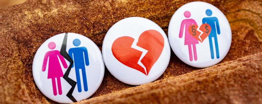 Three buttons with people and a broken heart on them